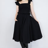Model wearing a black shirred flutter sleeve cotton blouse with a matching black skirt.