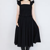 Model wearing a black shirred flutter sleeve cotton blouse with a matching black skirt.