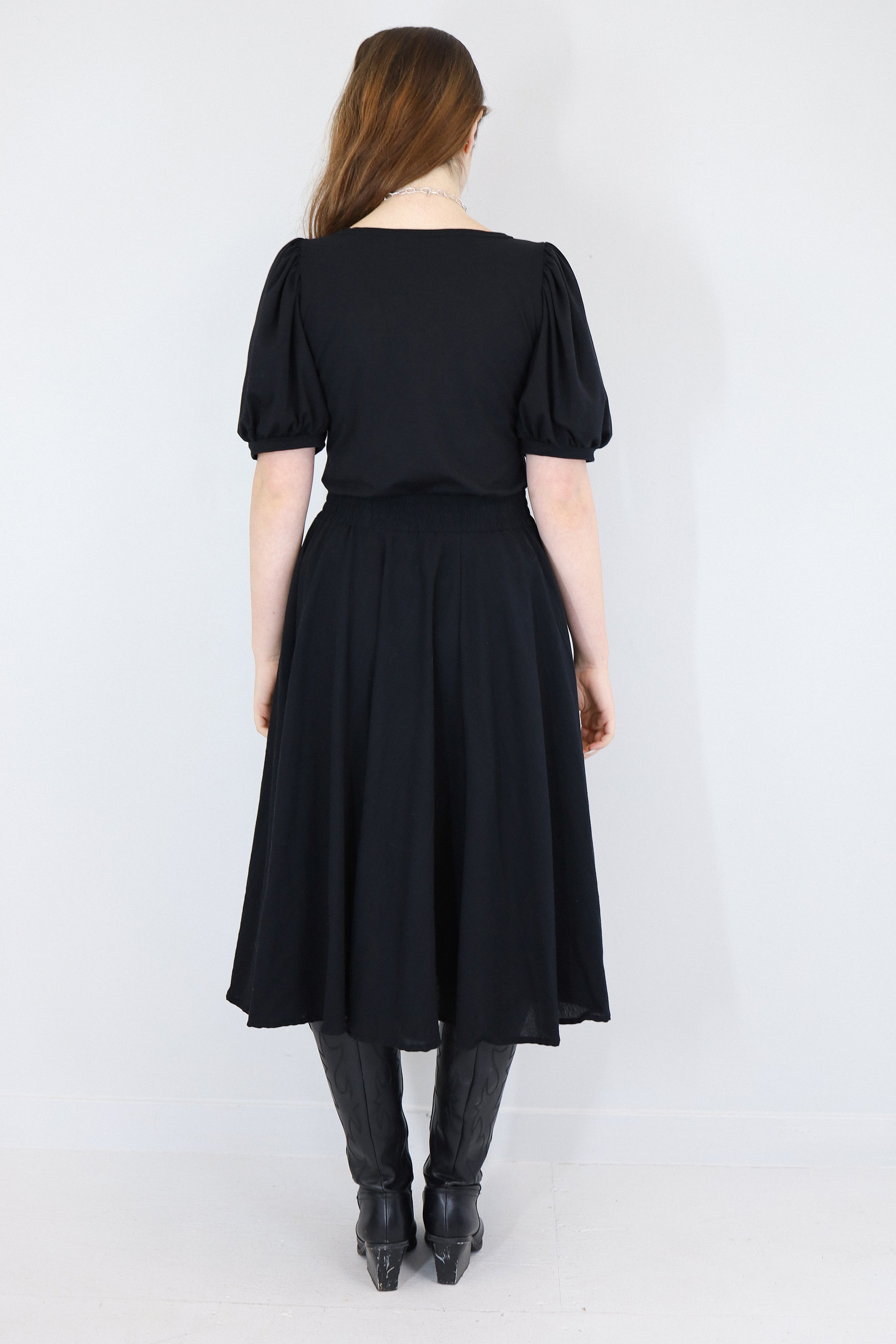 Model wearing a black twirl circle skirt facing back