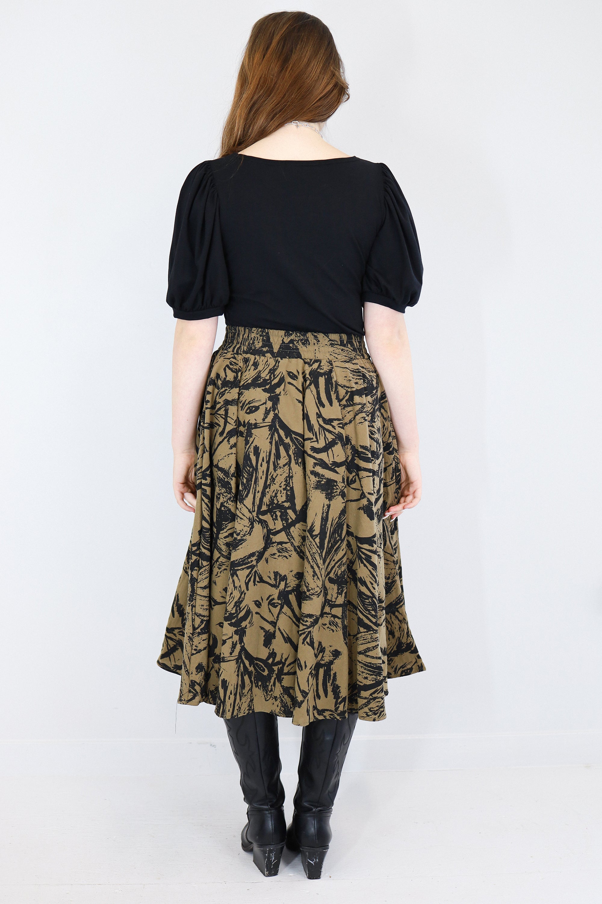 Model wearing a brown twirl circle skirt in a fox print facing backwards