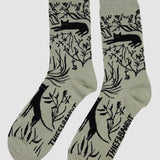 Pair of socks with black animal and plant pattern on a light gray background