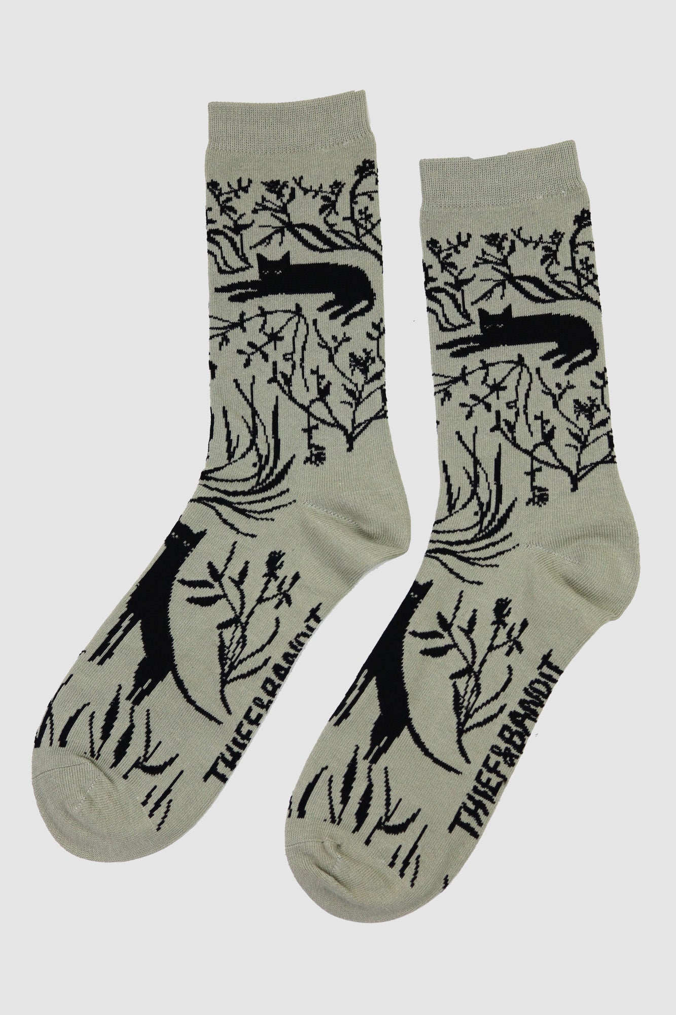 Pair of socks with black animal and plant pattern on a light gray background