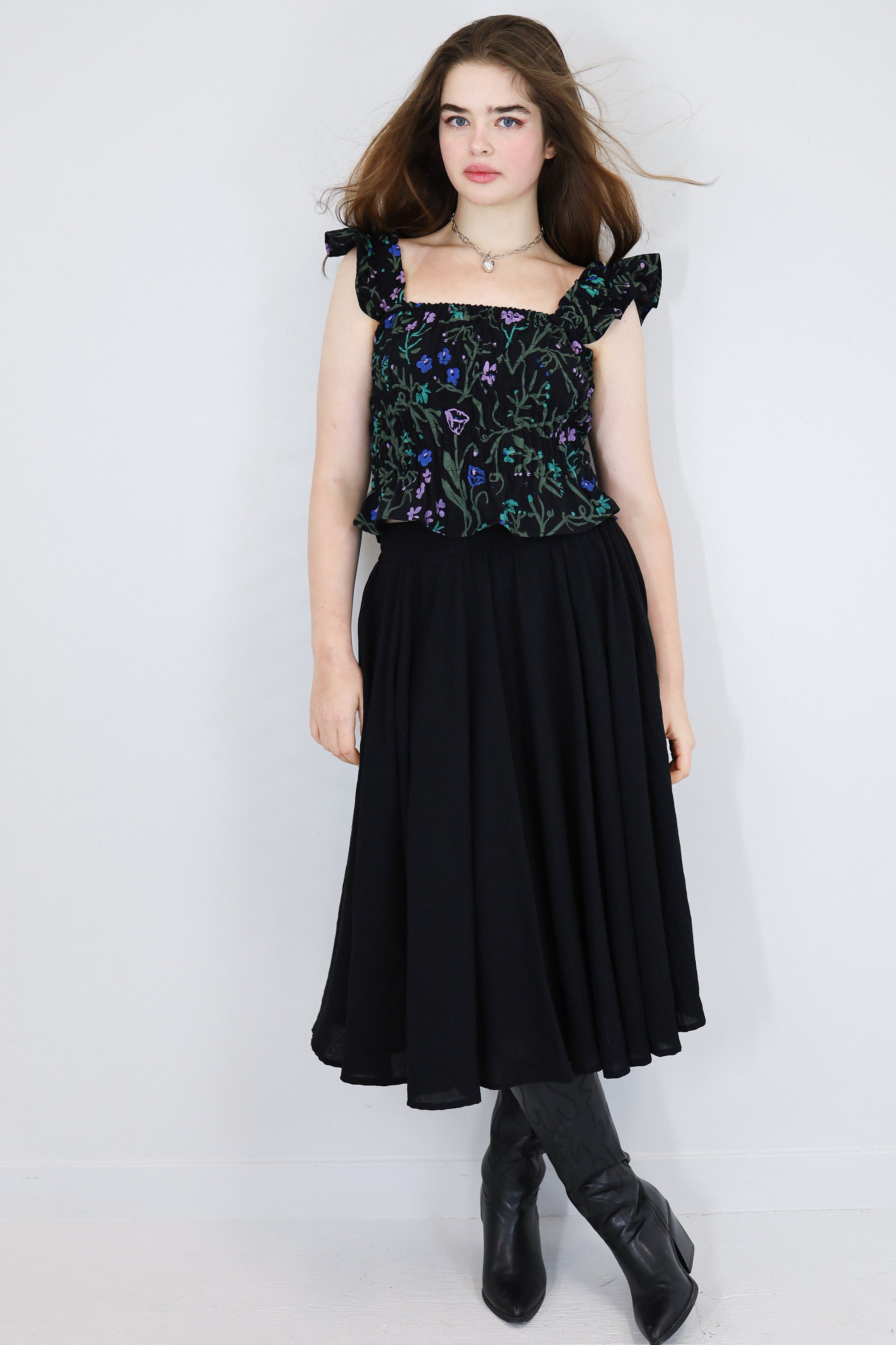 Model wearing a black floral print shirred flutter sleeve cotton blouse  paired with a matching black skirt.