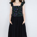 Model wearing a black floral print shirred flutter sleeve cotton blouse  paired with a matching black skirt.