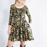 Model wearing a gold on black mushroom dress in a fit and flare twirl styled with black cowboy boots.