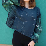 Person wearing a dark blue sweatshirt with star patterns against a teal wall.