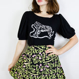 Woman wearing a black t-shirt with a tiger design and a floral skirt on a white background