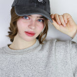 Person wearing a dark gray cap with a logo on a plain background