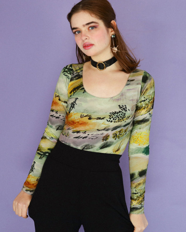 Woman wearing a colorful long-sleeve top with a pattern against a purple background