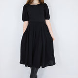 Model wearing a black twirl circle skirt with hands in pockets