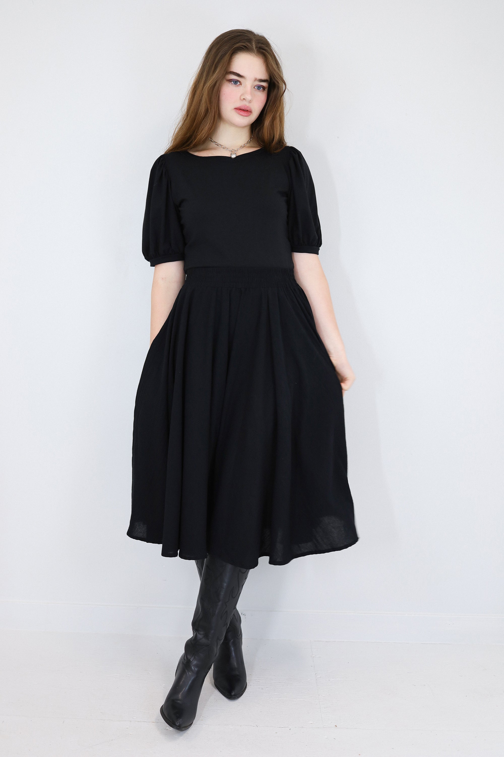 Model wearing a black twirl circle skirt with hands in pockets