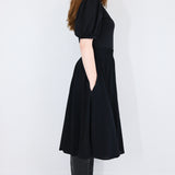 Model facing sideways wearing a black twirl circle skirt.