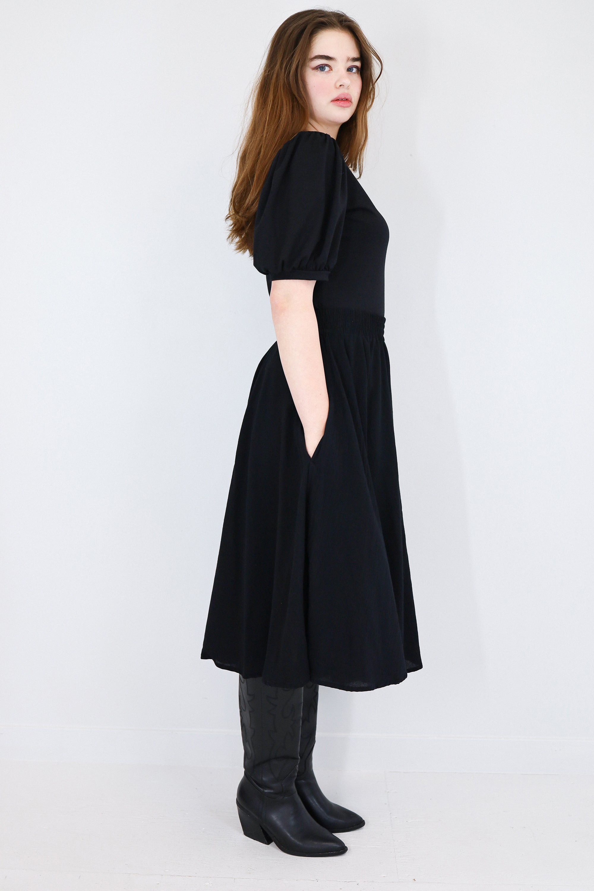 Model facing sideways wearing a black twirl circle skirt.